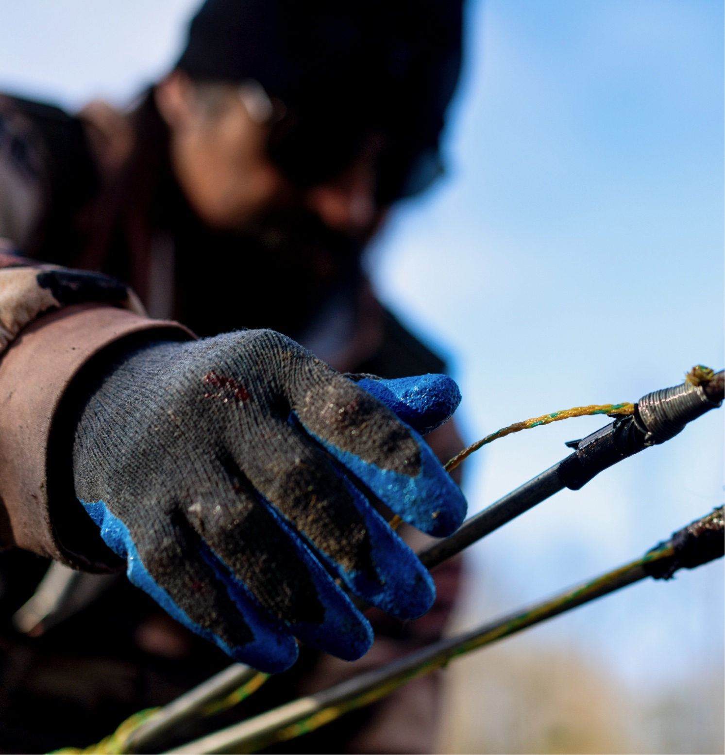 Gloved hand holding a stick with blurred background.