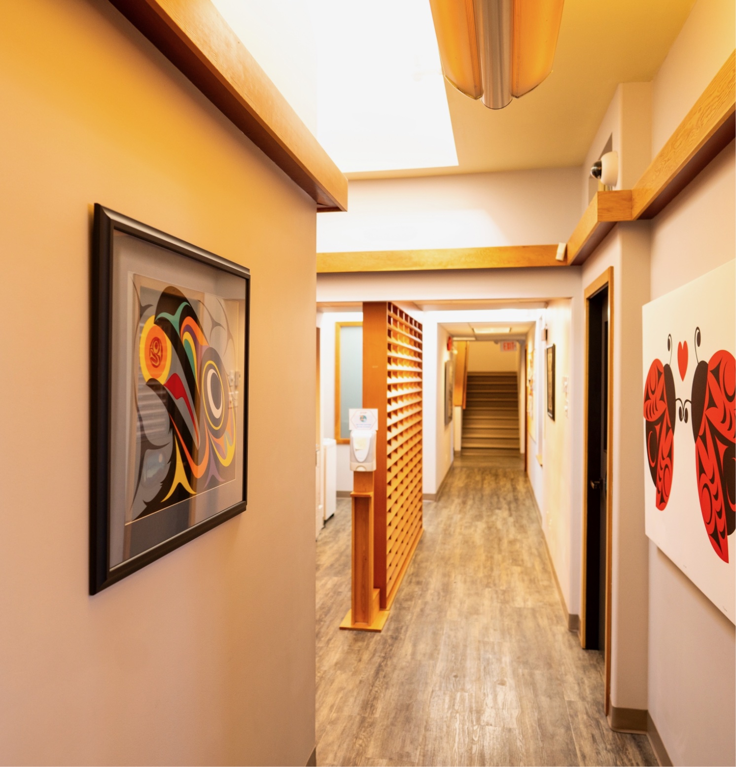 The hallway is empty and has paintings on the walls.