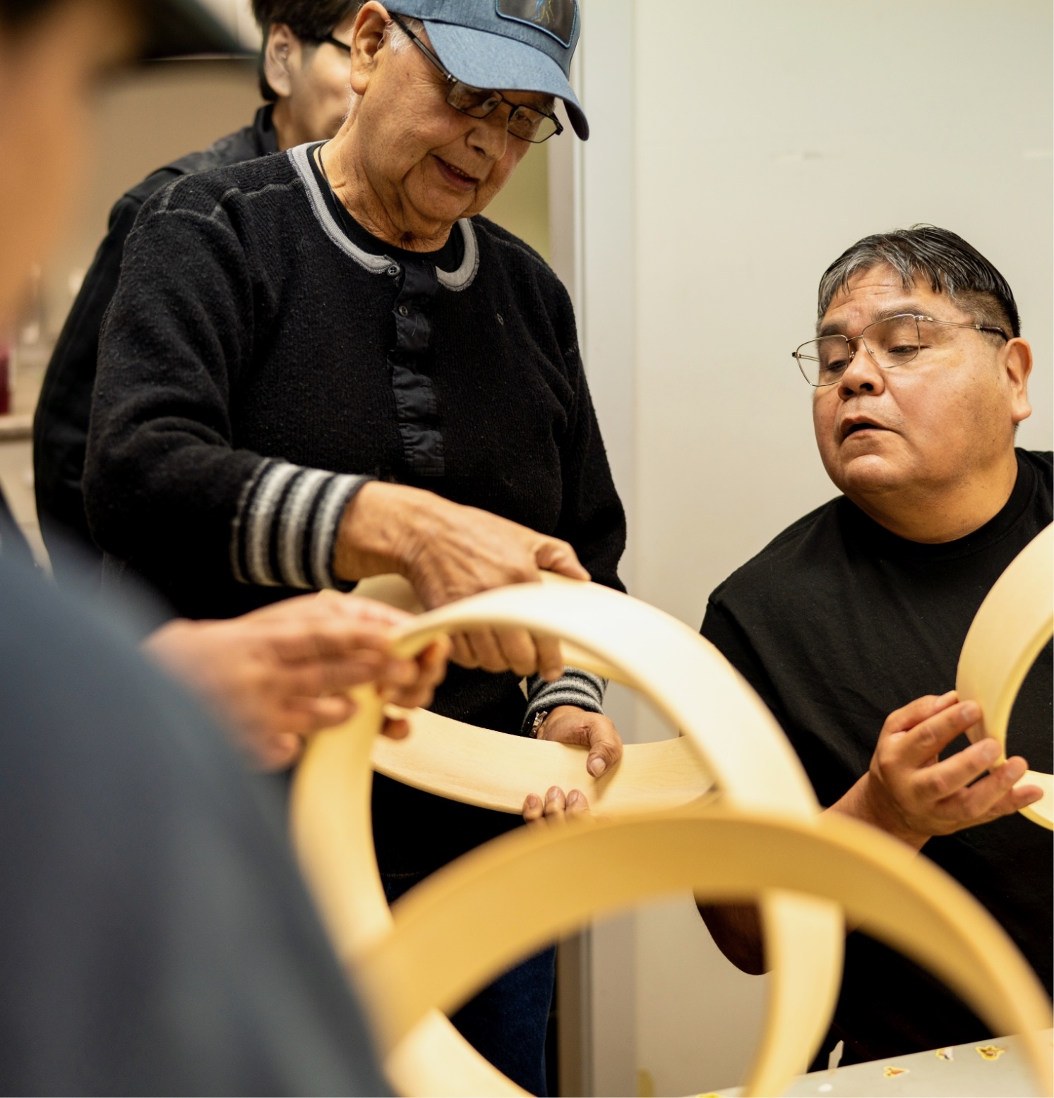 Two men holding a wooden circle with hands blurred due to motion or camera effect.