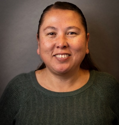 A woman smiles against a grey background