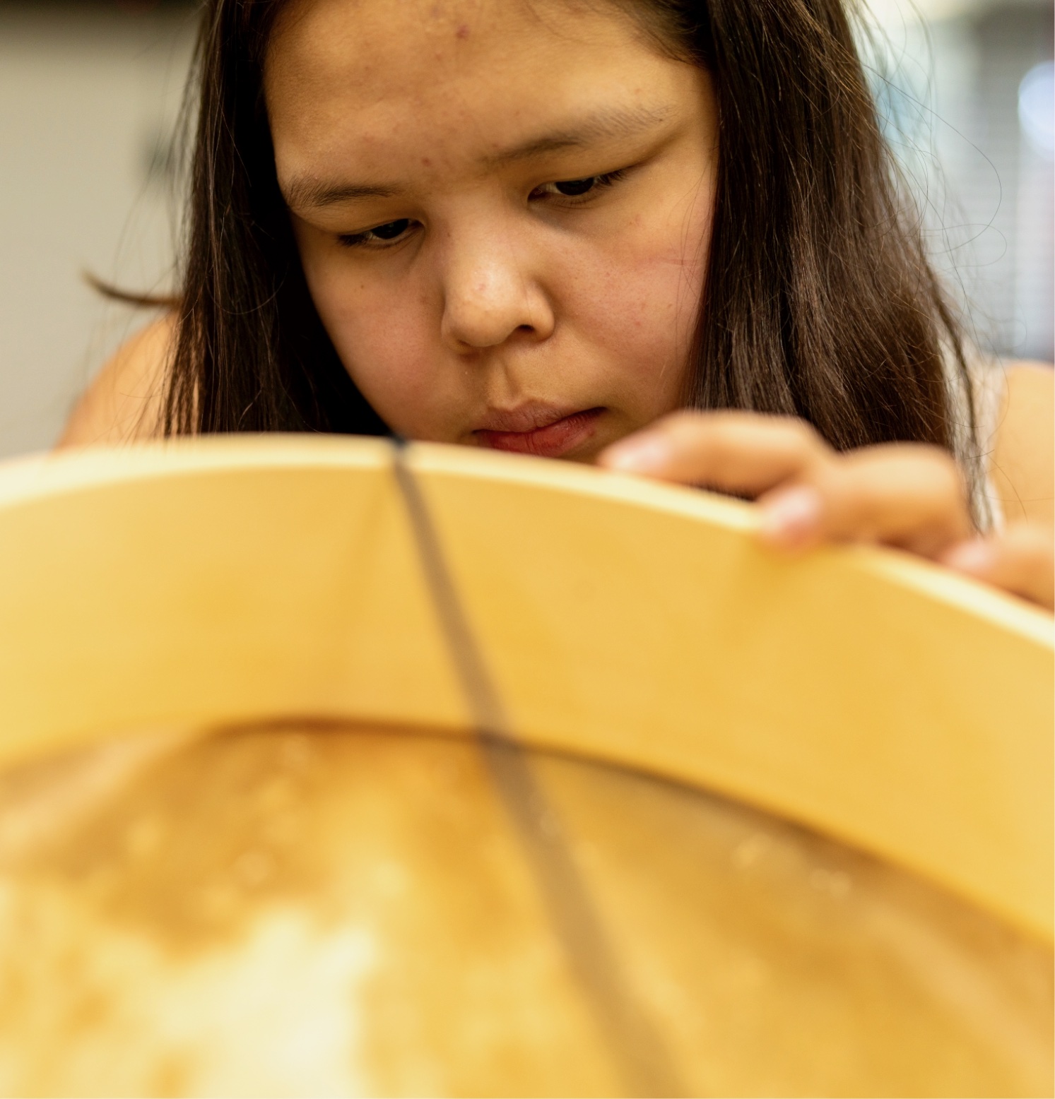 A person is holding a round object with their hands and looking at it closely.