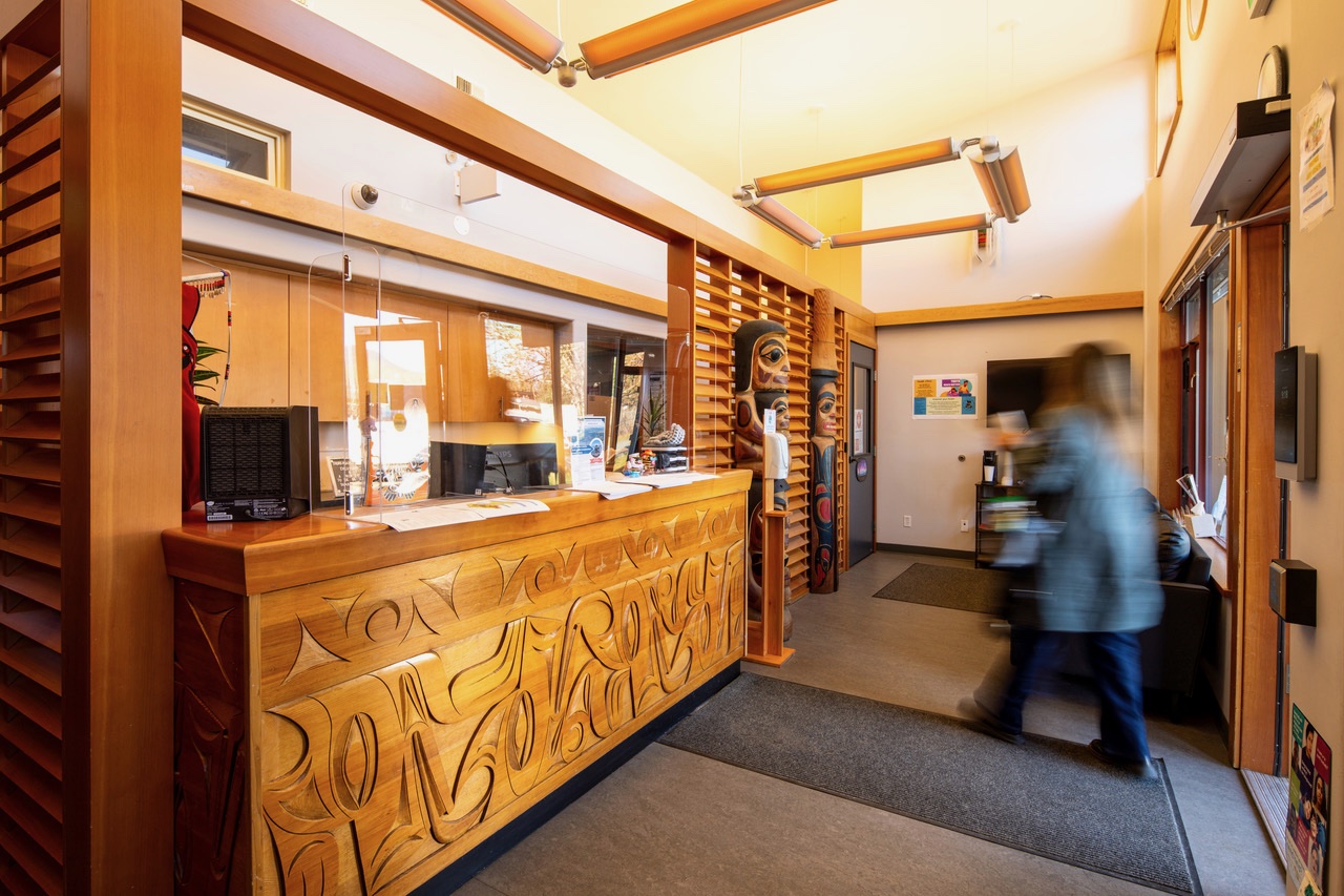 A person is walking through a building with an office reception and various items hanging from the ceiling.