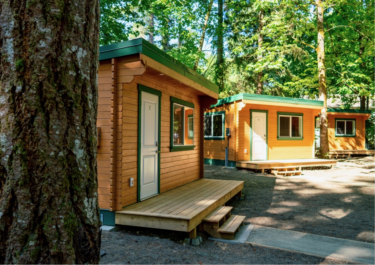 The photo shows a wooden cabin surrounded by trees with overcast sky and overexposed areas.