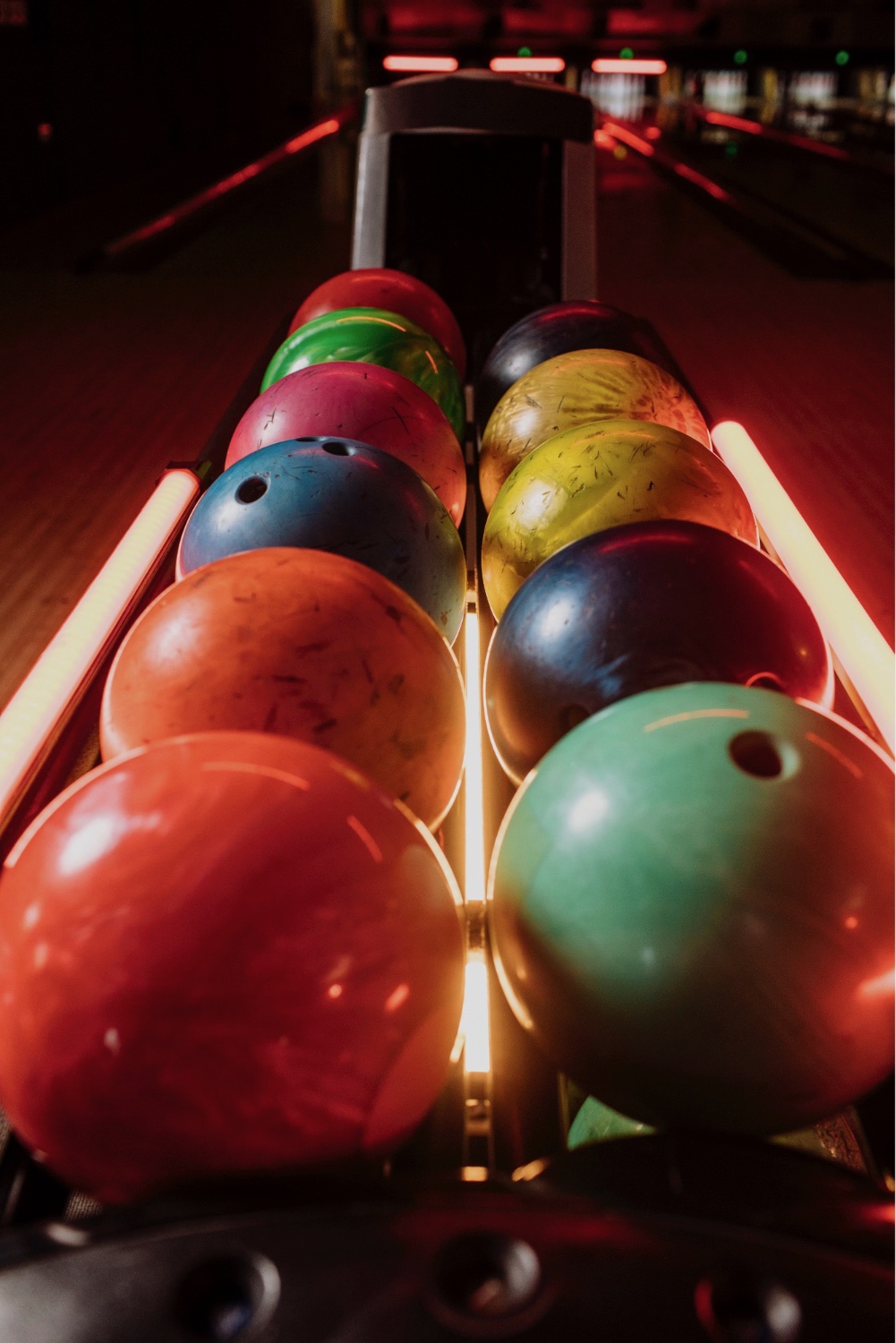 A blurry photo of a bowling alley with balls and pins.